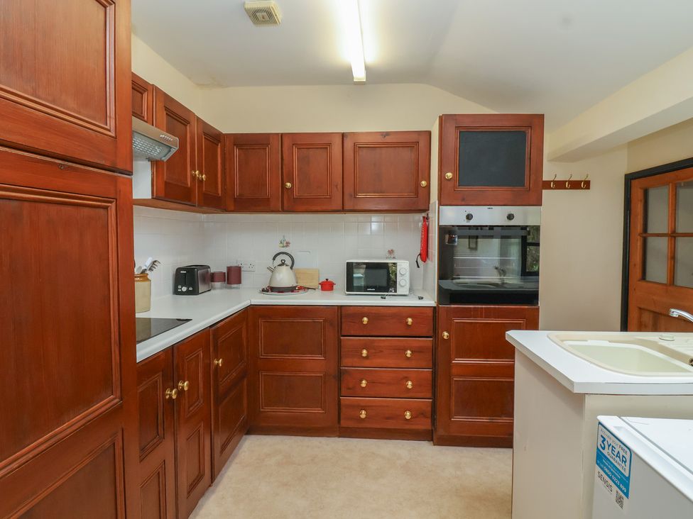 A kitchen with cabinets, oven, microwave, toaster, kettle, and sink at The Cottage in Bridgwater