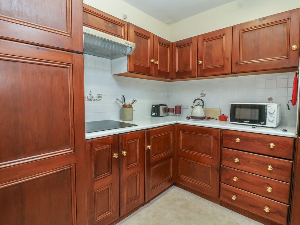 A kitchen with wooden cabinets and appliances at The Cottage in Bridgwater
