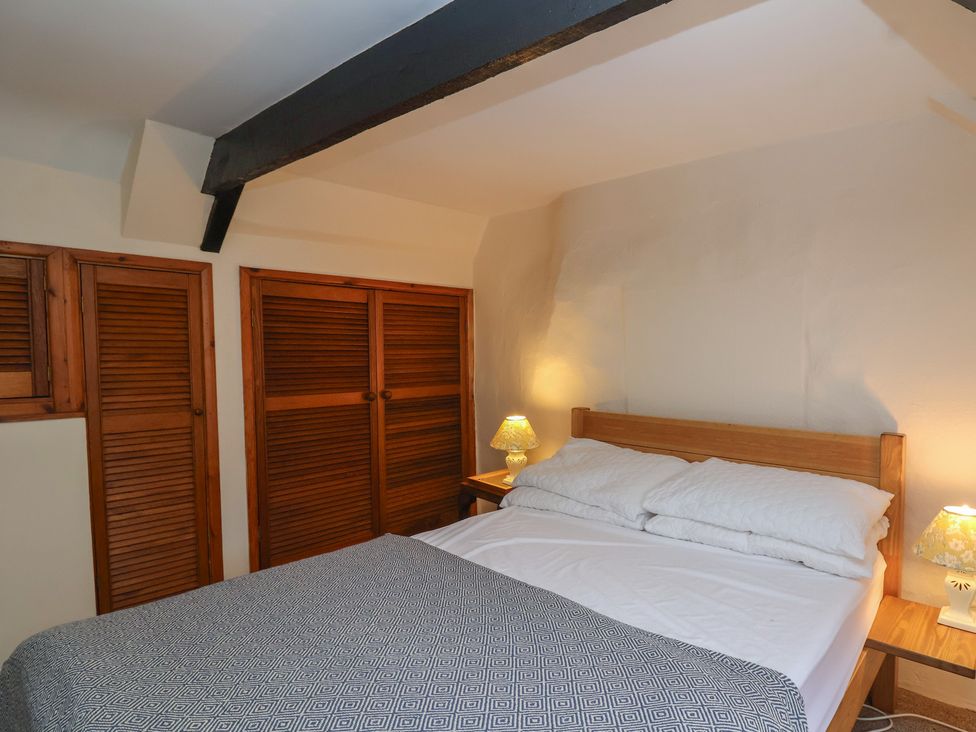 A bedroom with a bed and wooden furniture at The Cottage in Bridgwater