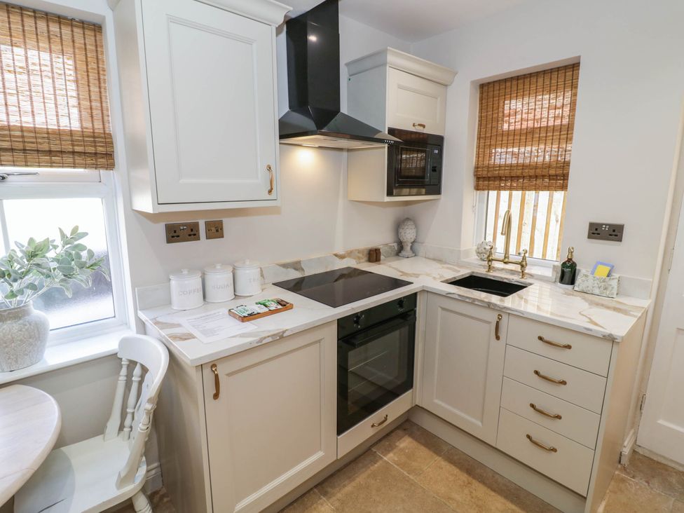 A kitchen with cabinets, cooker, and sink at Albert Cottage Stratford-upon-Avon