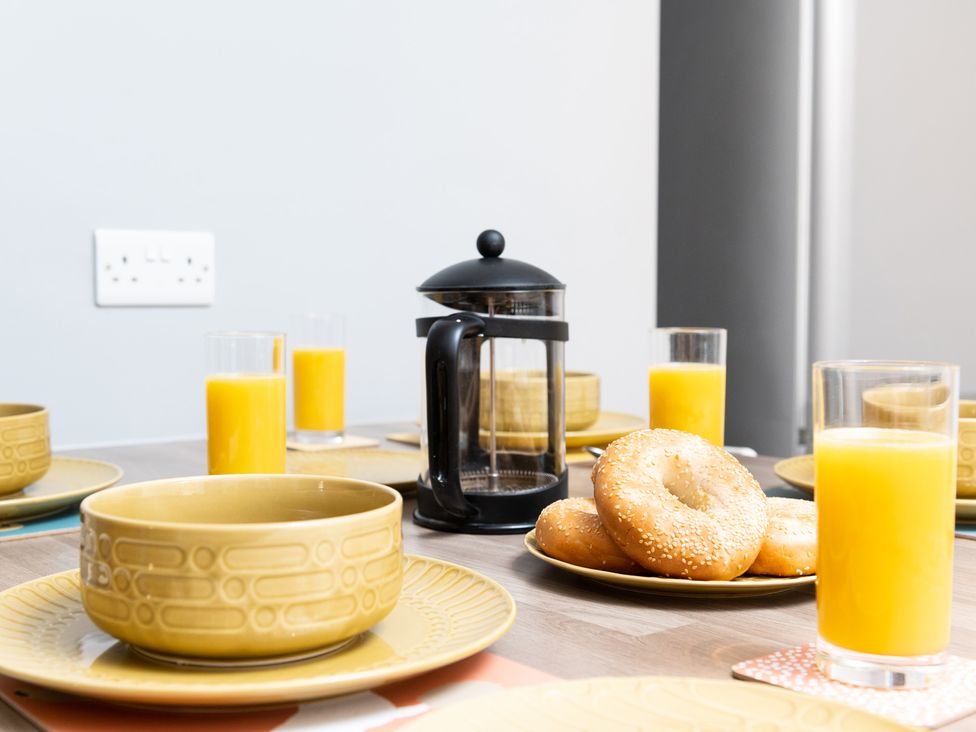 A dining table set with bowls, glasses of orange juice, bagels and a coffee press at 38 Ashville Avenue Scarborough