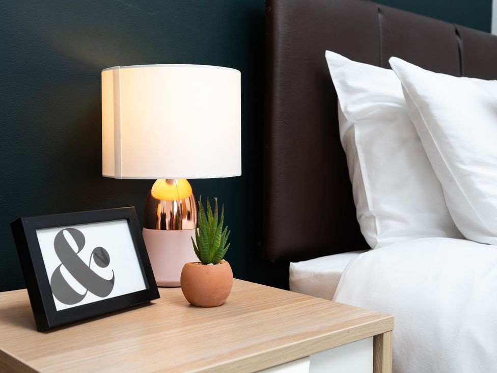 A bedside table with a lamp and a picture frame in a bedroom at 38 Ashville Avenue, Scarborough