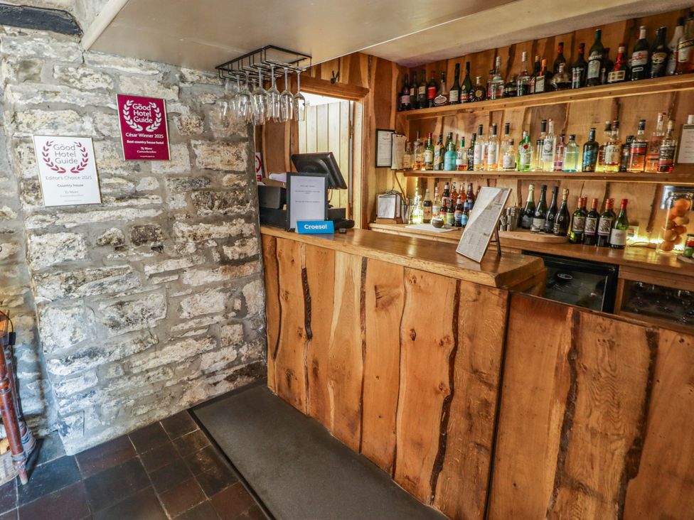 A bar area with bottles on shelves and a counter at Ty Mawr Country House in Carmarthen