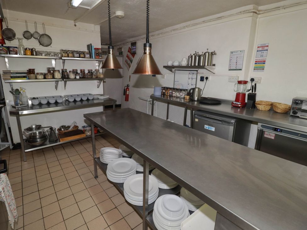 A kitchen with metal tables and shelves containing kitchen utensils at Ty Mawr Country House in Carmarthen