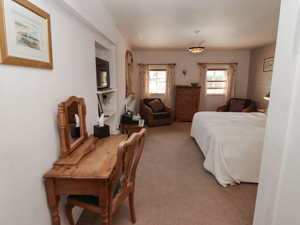 A bedroom with a bed and dressing table at Ty Mawr Country House in Carmarthen