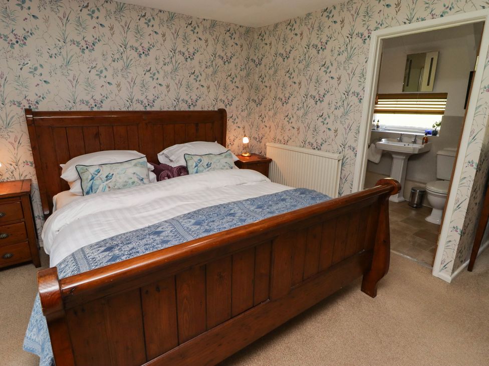 A bedroom with a wooden bed and nightstand at Ty Mawr Country House, Carmarthen