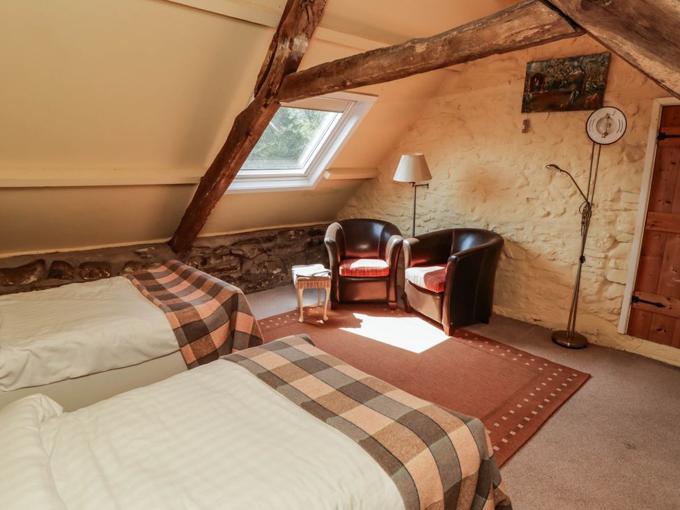 A bedroom with two beds and armchairs at Ty Mawr Country House in Carmarthen