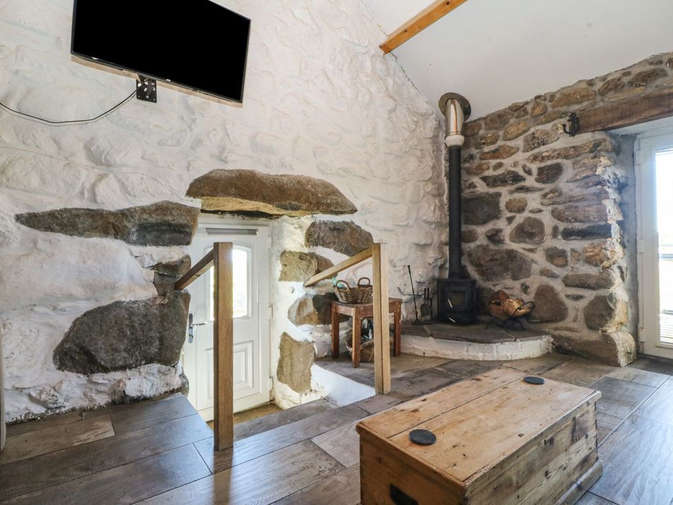 A living room with a stove and a wooden box at Ty Coch in Caernarfon