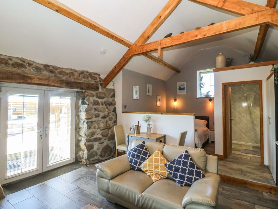 A living room with a sofa and dining area at Ty Coch in Caernarfon