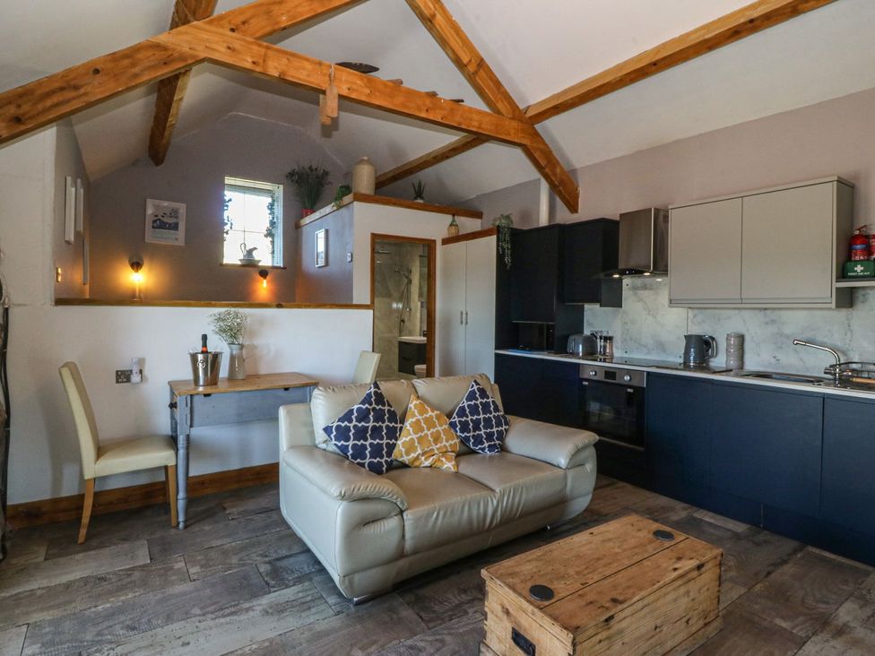A living room with a sofa and dining area at Ty Coch in Caernarfon