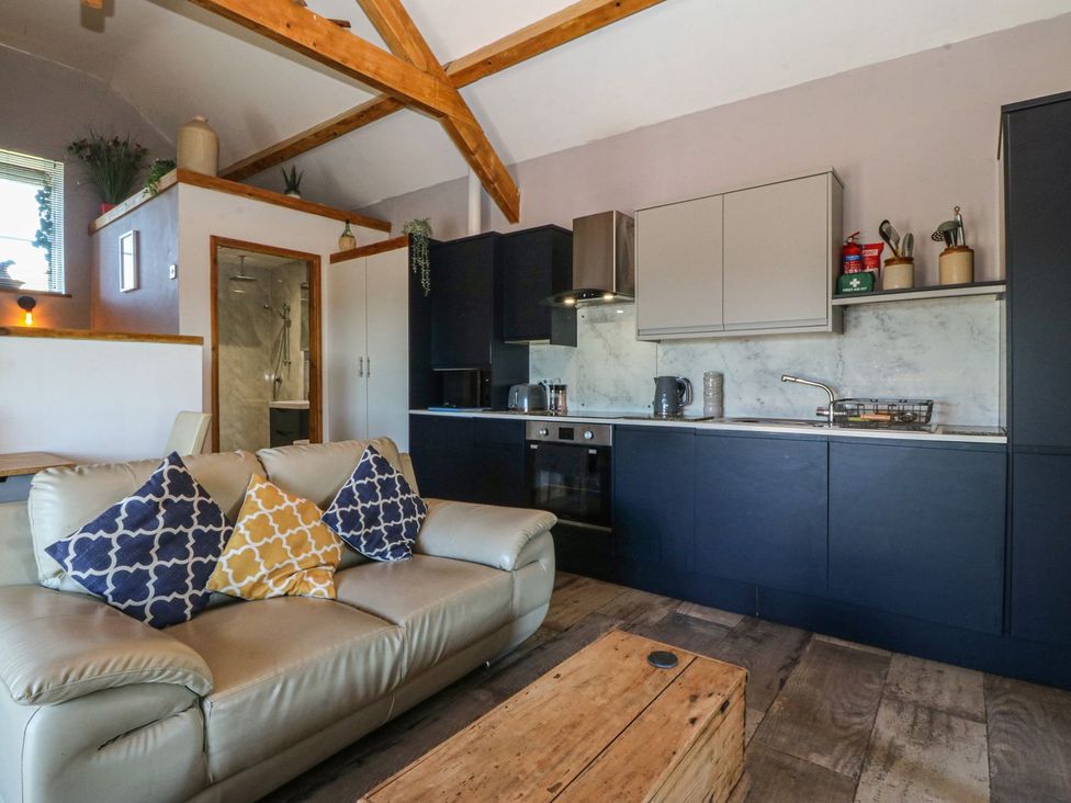 A living room with a kitchen area and a sofa at Ty Coch in Caernarfon