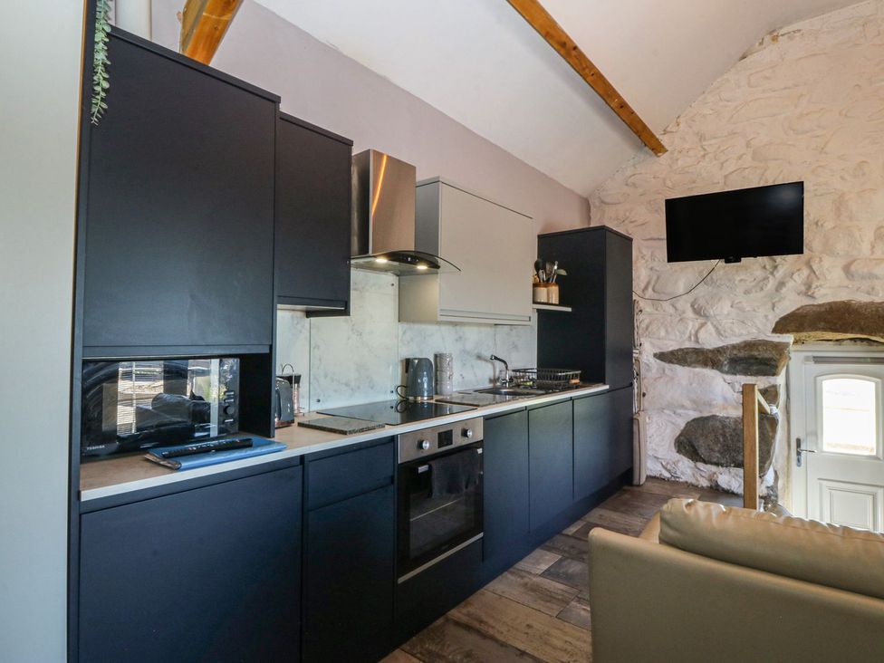 A kitchen with cabinets stove and microwave at Ty Coch in Caernarfon