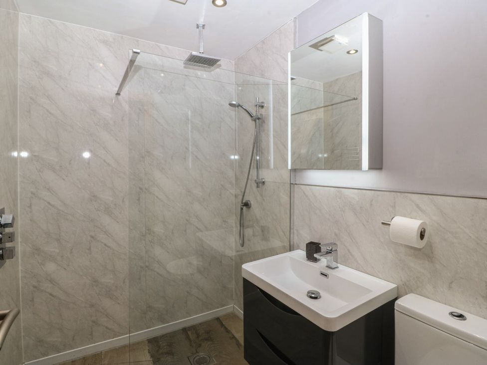 A bathroom with a shower, sink, and toilet at Ty Coch in Caernarfon