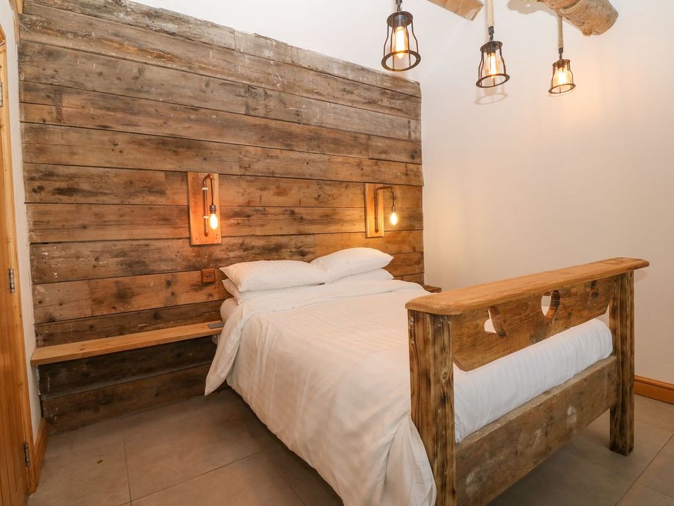 A bedroom with a bed and wooden wall at Cefnbron in Caernarfon