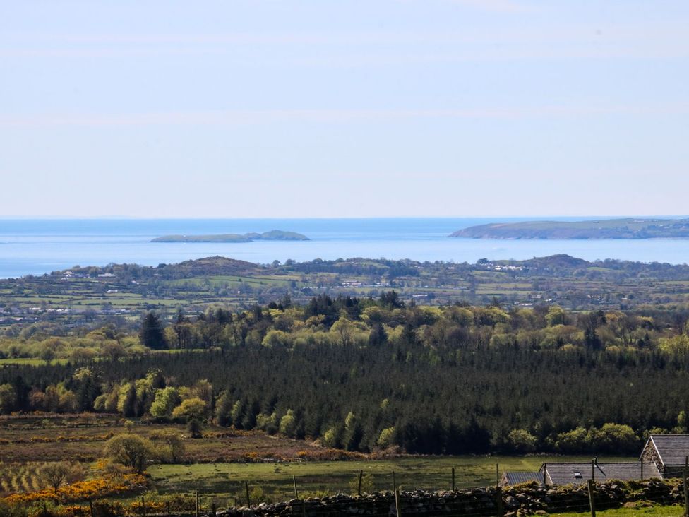 A view of the sea and islands with trees and fields at Cefnbron Caernarfon