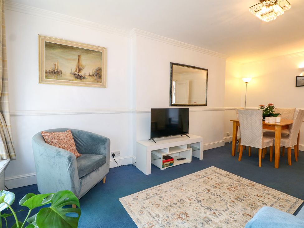 A living room with a television and dining table at 4 Sussex Close in Watford