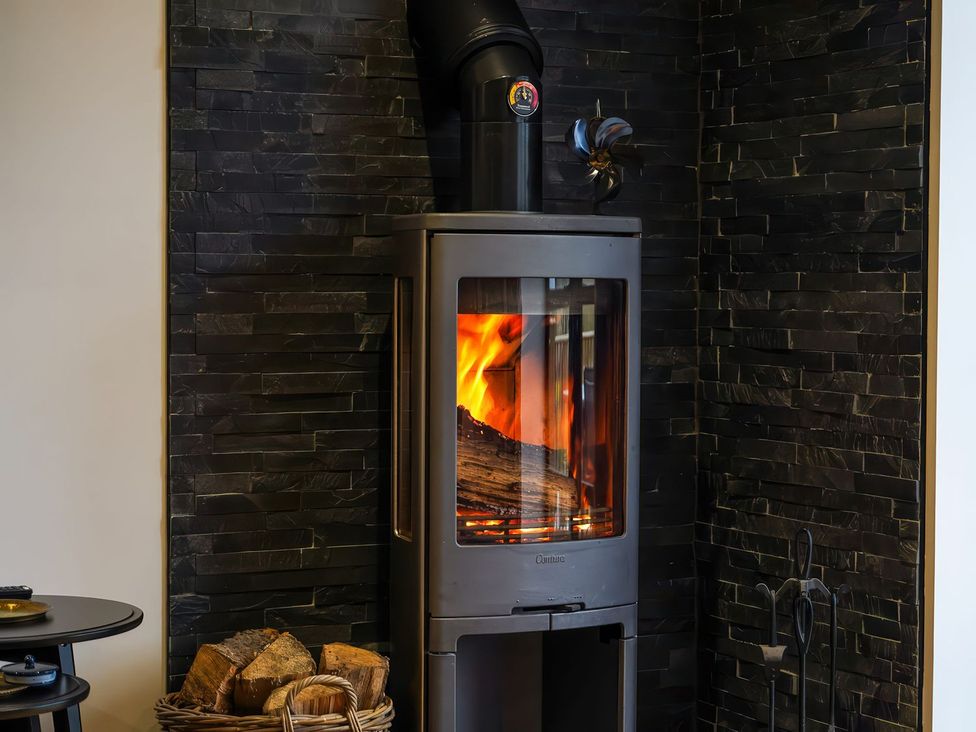 A wood stove with fire and firewood in a basket at The Old Mill Great Bolas near Telford