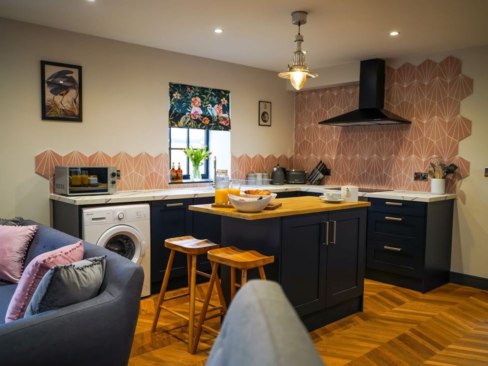 A kitchen with a stool and washing machine at The Old Mill Great Bolas near Telford