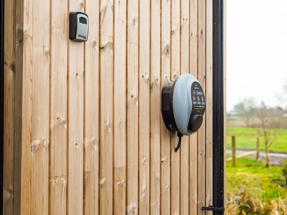 An electric vehicle charging station on a wooden wall at The Old Mill in Great Bolas near Telford