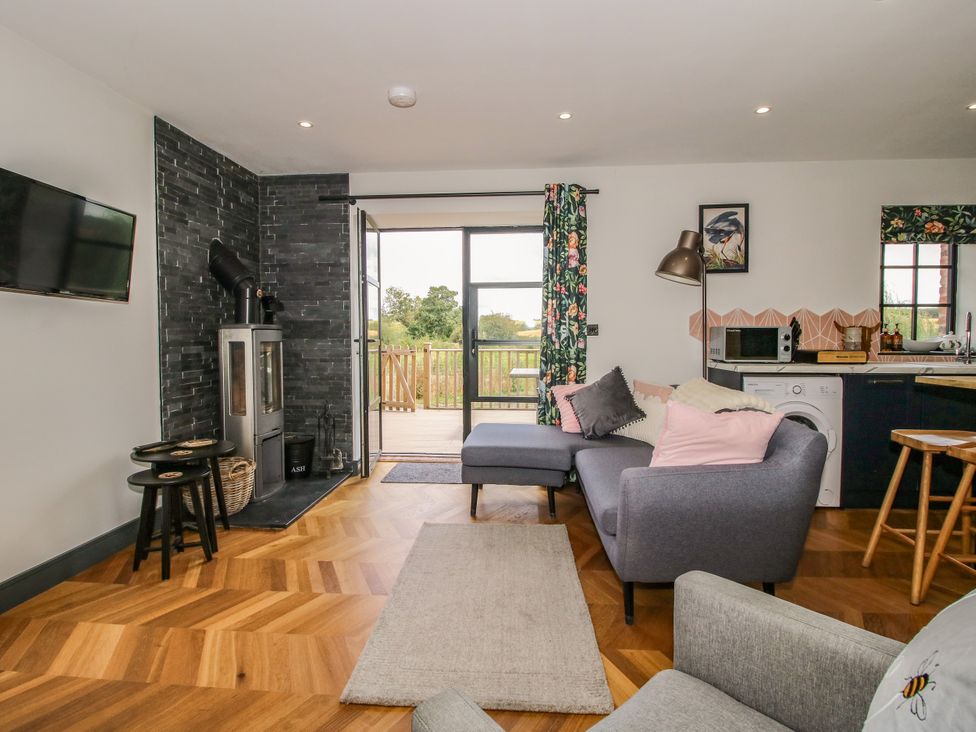 A living room with a sofa and kitchen area at The Old Mill in Great Bolas near Telford