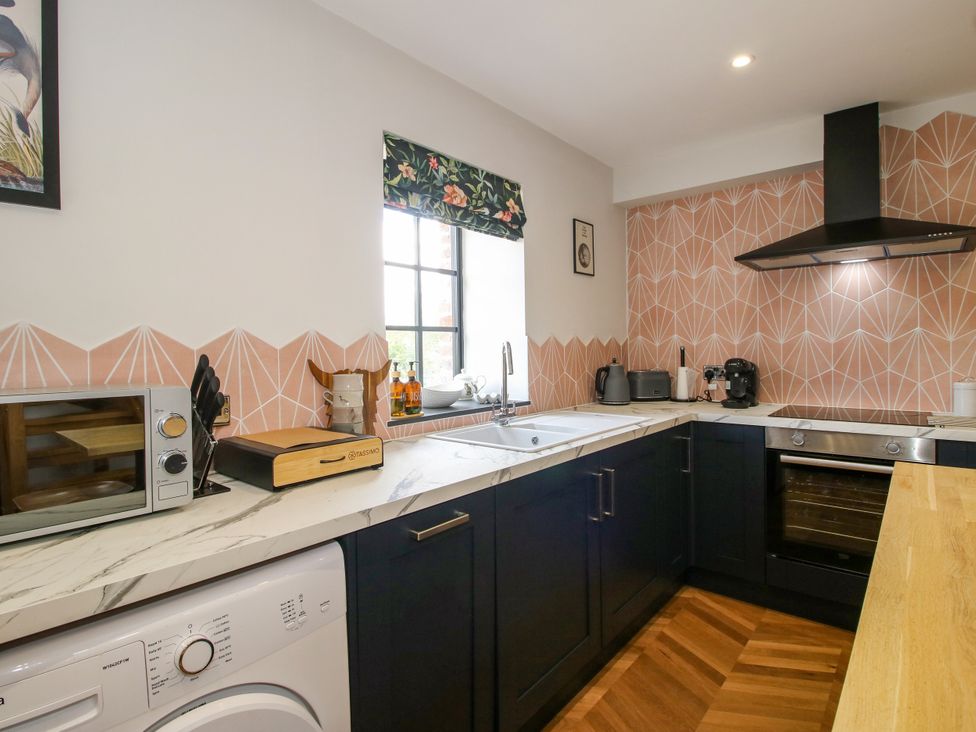 A kitchen with a microwave, washing machine, and a sink at The Old Mill in Great Bolas near Telford