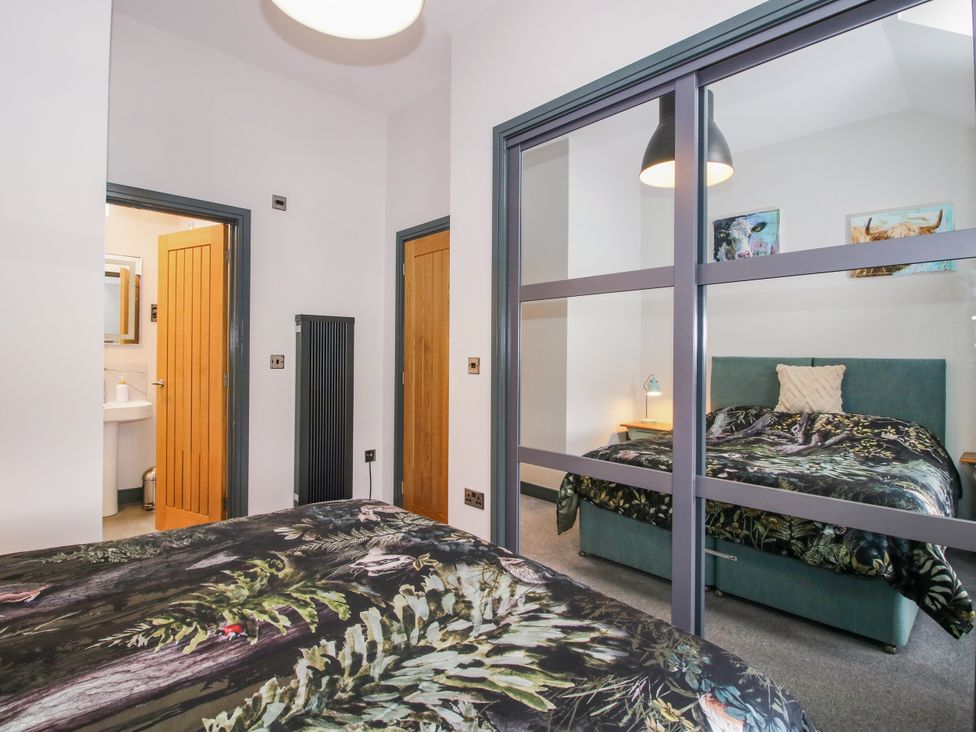 A bedroom with two beds and a door leading to a bathroom at The Old Mill in Great Bolas near Telford