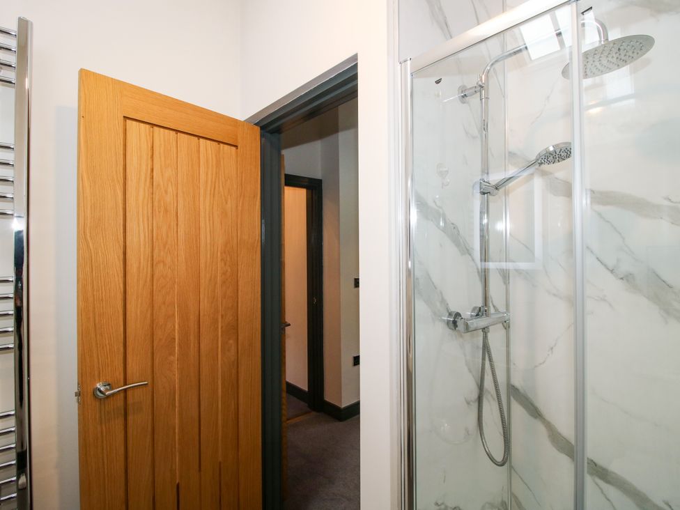 A bathroom with a shower and wooden door at The Old Mill in Great Bolas near Telford
