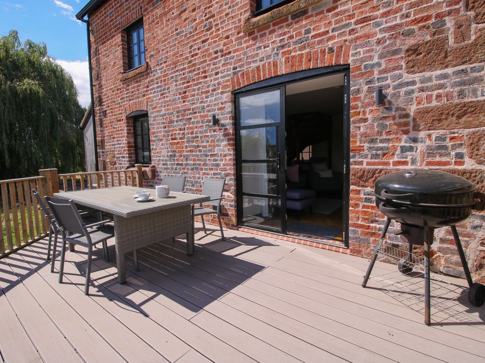 An outdoor patio with a table, chairs and a barbecue at The Old Mill in Great Bolas near Telford