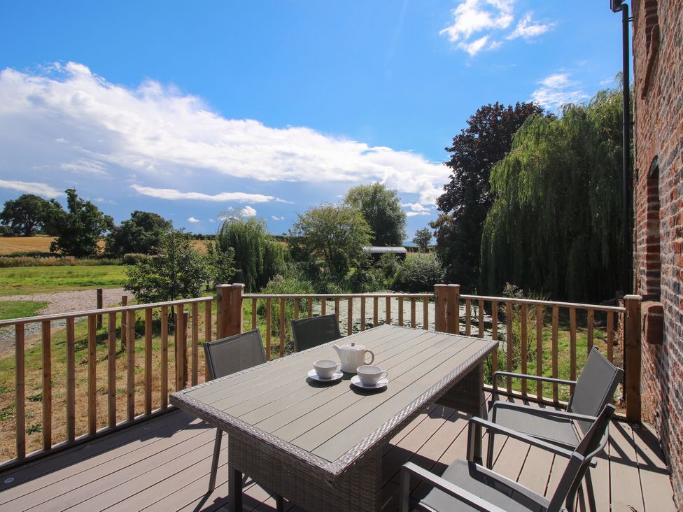 A deck with a table and chairs overlooking a field at The Old Mill in Great Bolas near Telford