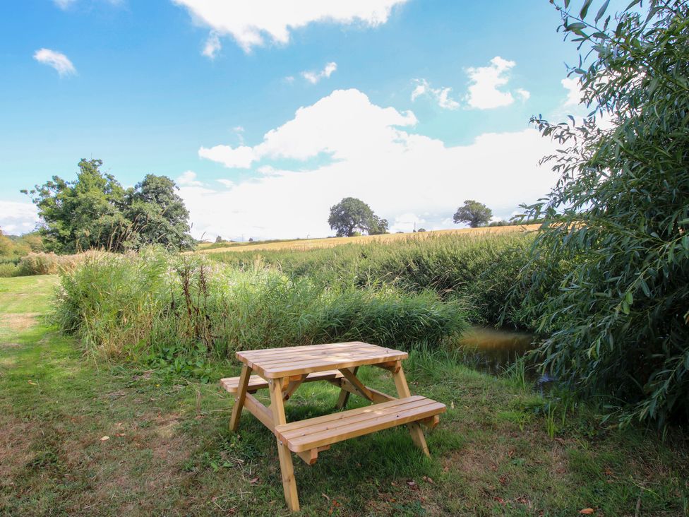 A picnic table in a field near a stream at The Old Mill Great Bolas near Telford