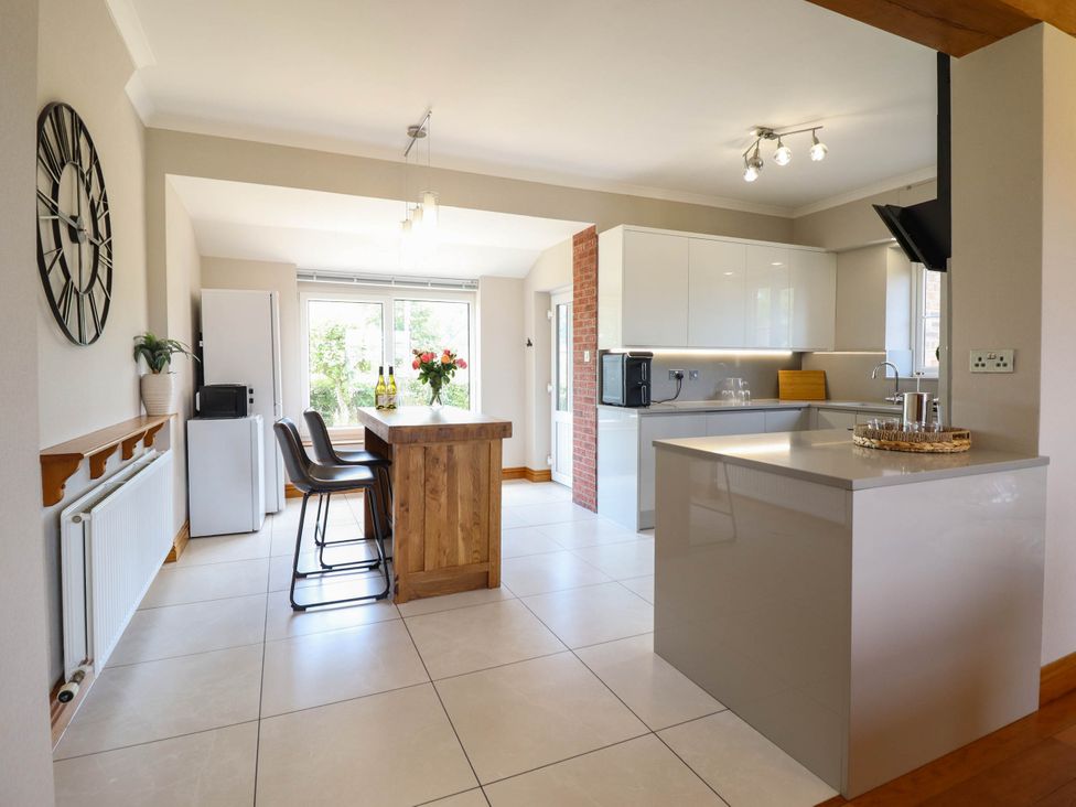 A kitchen with a countertop and stools at Pwll Glas in Caersws
