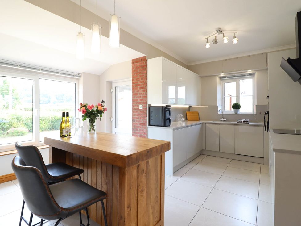 A kitchen with a wooden table and chairs at Pwll Glas in Caersws