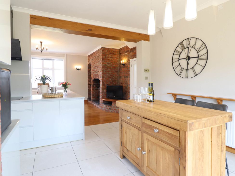 A kitchen with a central island and a view of the living area at Pwll Glas in Caersws