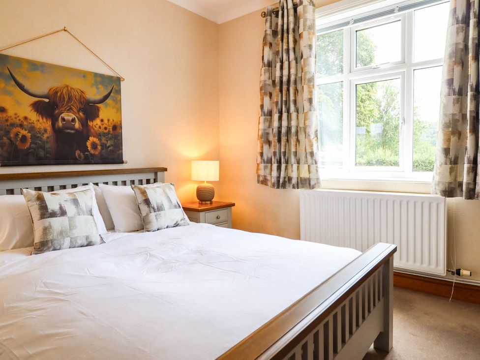 A bedroom with a bed and lamp at Pwll Glas in Caersws