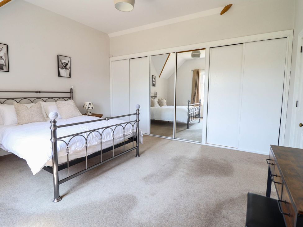 A bedroom with a bed and mirrored wardrobe at Pwll Glas in Caersws