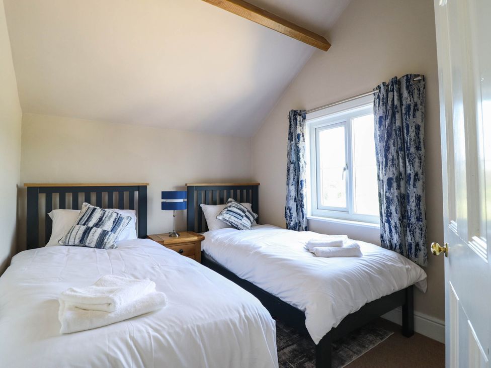 A bedroom with two beds and a window at Pwll Glas in Caersws