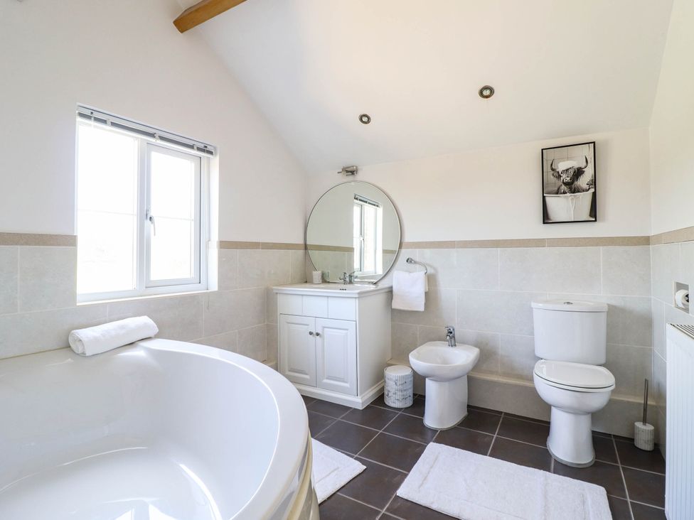 A bathroom with a bathtub and sink at Pwll Glas in Caersws