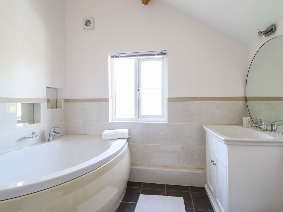 A bathroom with a bathtub and sink at Pwll Glas in Caersws