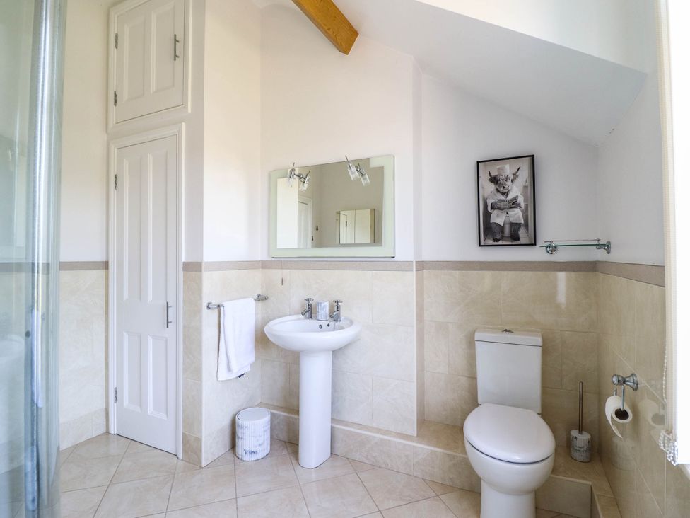 A bathroom with a sink, toilet, and shower at Pwll Glas in Caersws