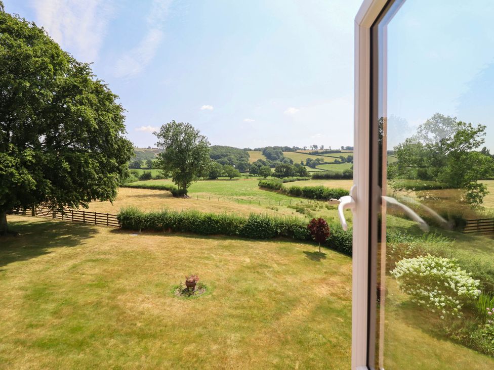 A view of a field and trees from a window at Pwll Glas in Caersws