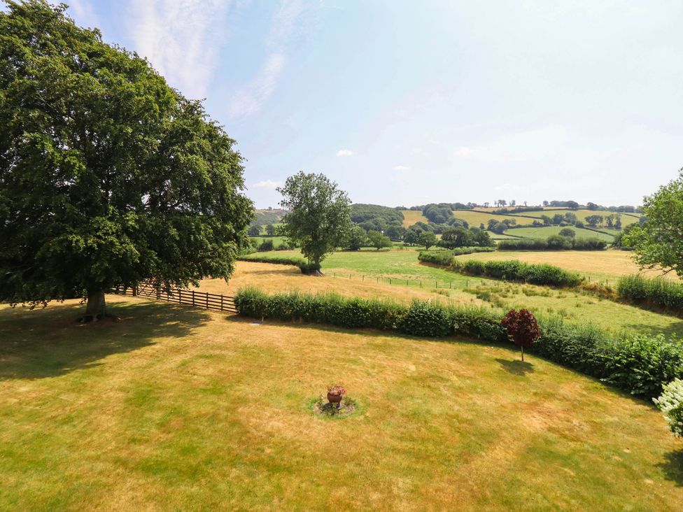 A view of a field with trees and a fence at Pwll Glas in Caersws