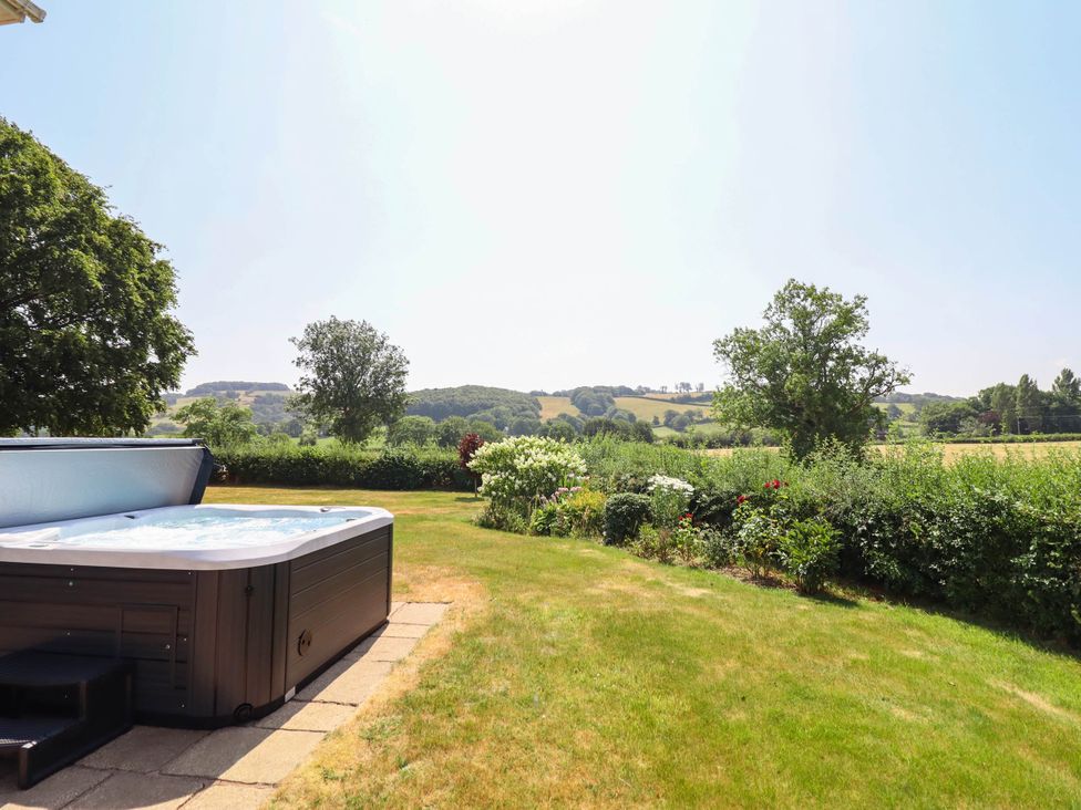 A hot tub in a garden with trees and grass at Pwll Glas in Caersws