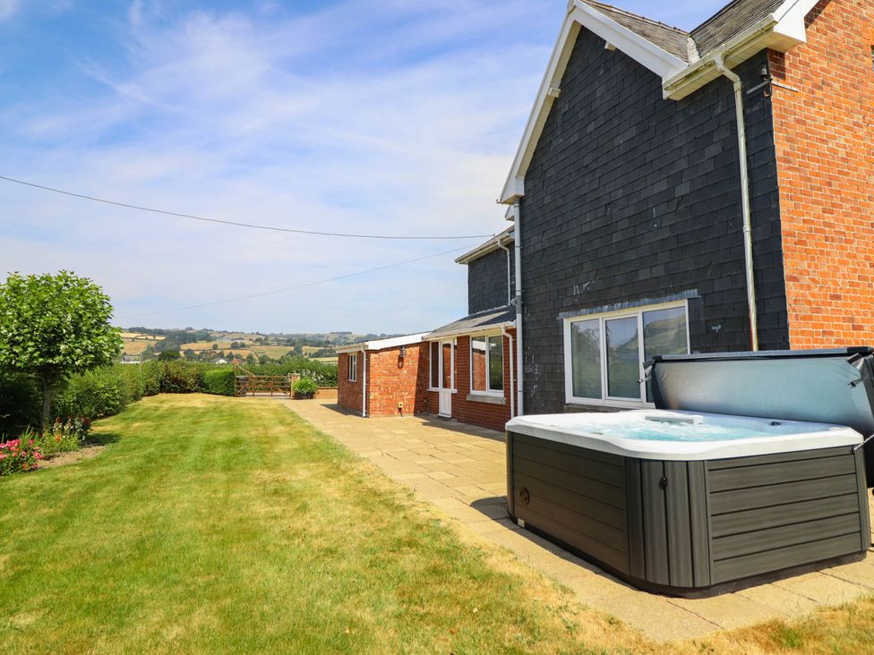 A garden with a hot tub and grass at Pwll Glas in Caersws