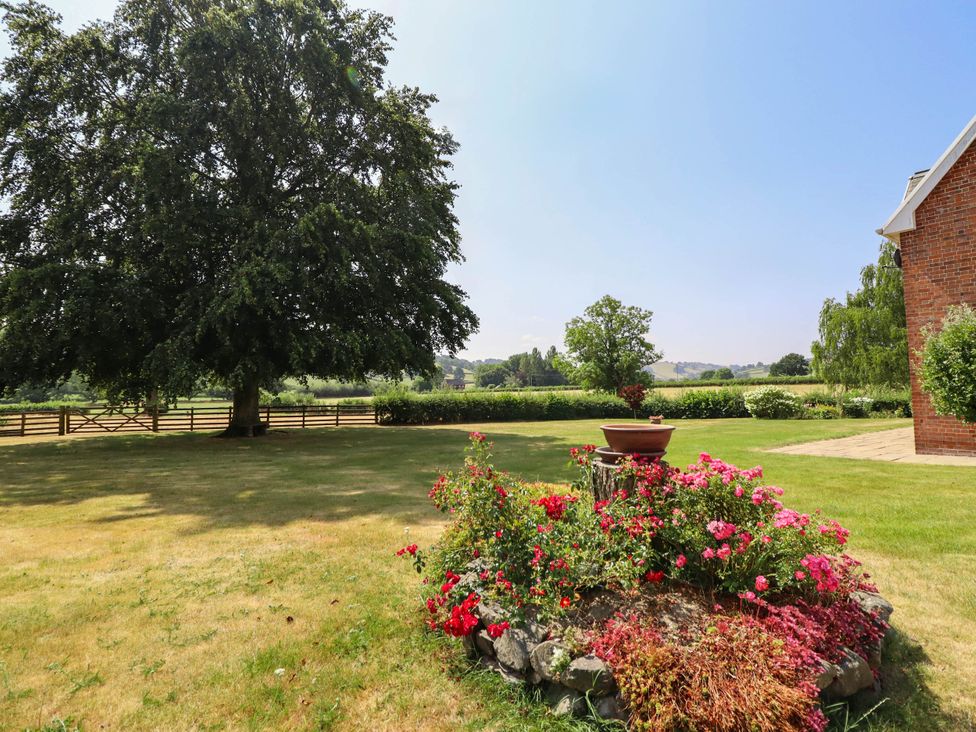 A garden with flowers and trees at Pwll Glas in Caersws