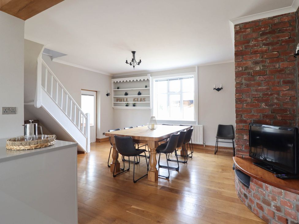 A dining room with a wooden table and chairs at Pwll Glas in Trefeglwys