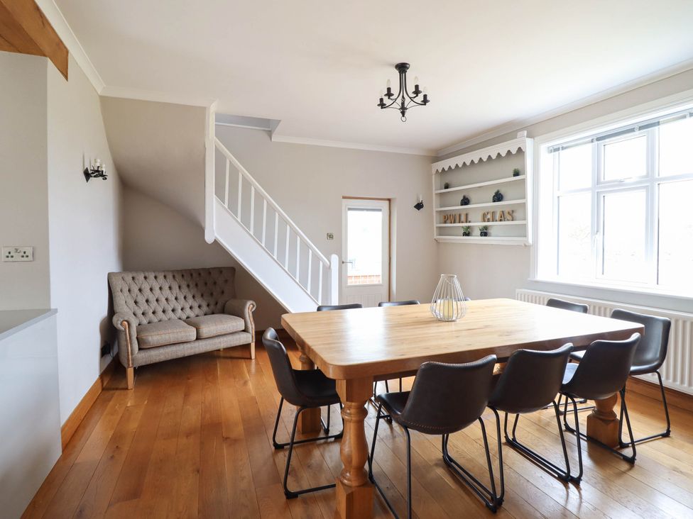 A dining room with a wooden table and chairs at Pwll Glas in Trefeglwys