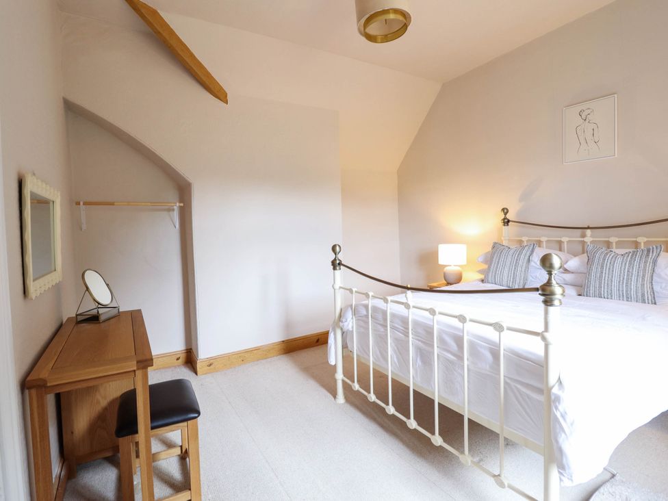 A bedroom with a bed and a table at Pwll Glas in Trefeglwys