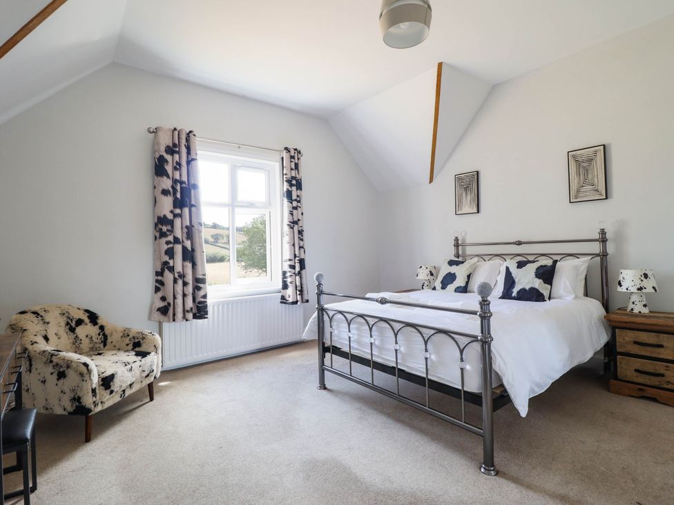 A bedroom with a bed and chair at Pwll Glas Trefeglwys