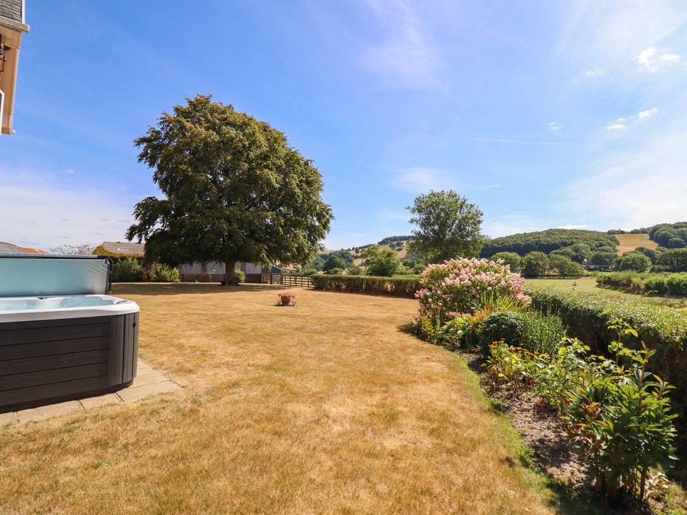 A garden with a hot tub and trees at Pwll Glas in Trefeglwys