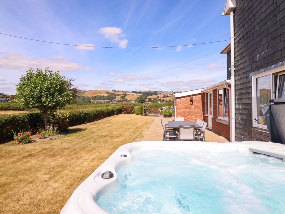 A garden with a hot tub and outdoor seating at Pwll Glas, Trefeglwys